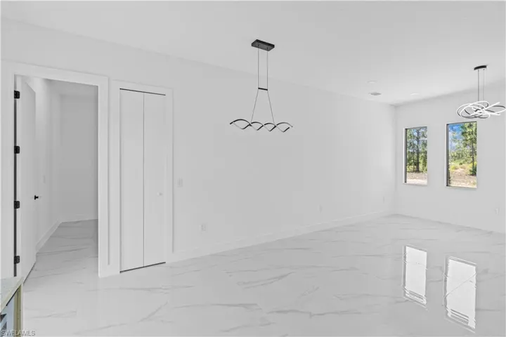 Unfurnished dining area featuring light marble finish floors and baseboards