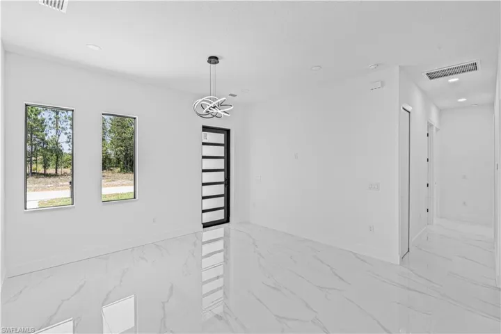 Empty room featuring light marble finish flooring, baseboards, and recessed lighting