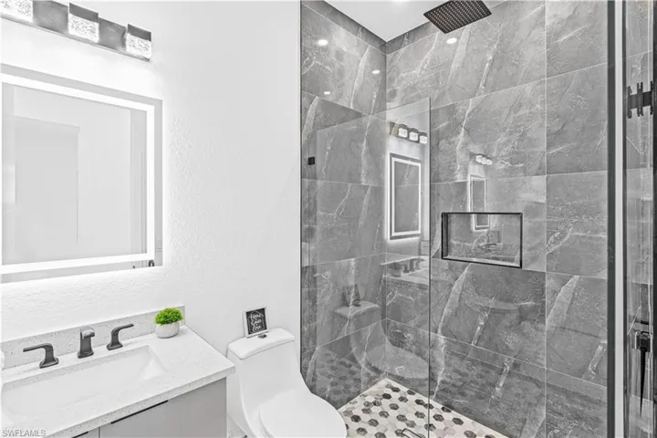 Full bathroom featuring tiled shower, toilet, and vanity