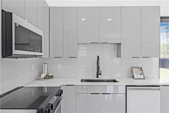 Kitchen with range with electric cooktop, a sink, dishwasher, modern cabinets, and backsplash