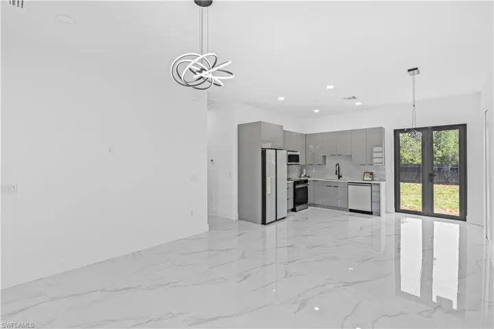Kitchen featuring gray cabinets, appliances with stainless steel finishes, modern cabinets, a sink, and light marble finish floors