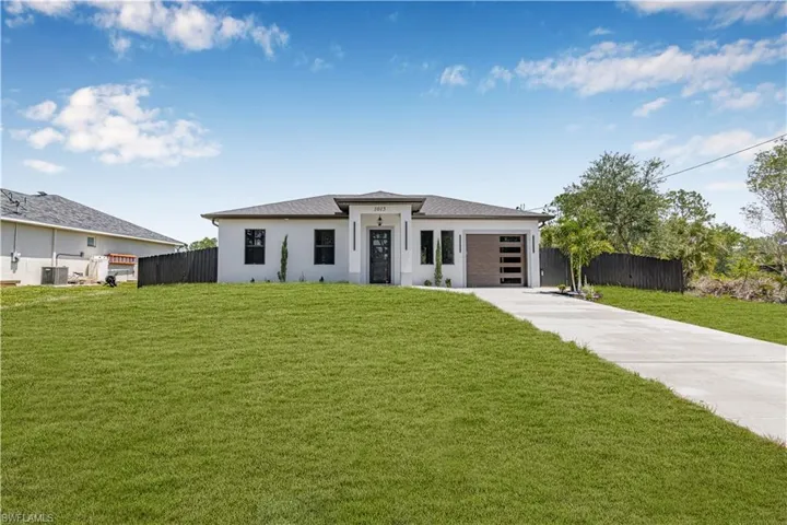 View of front of house with driveway, an attached garage, central AC unit, and stucco siding