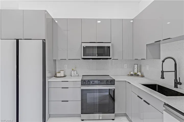 Kitchen with stainless steel appliances, a sink, gray cabinets, modern cabinets, and light countertops