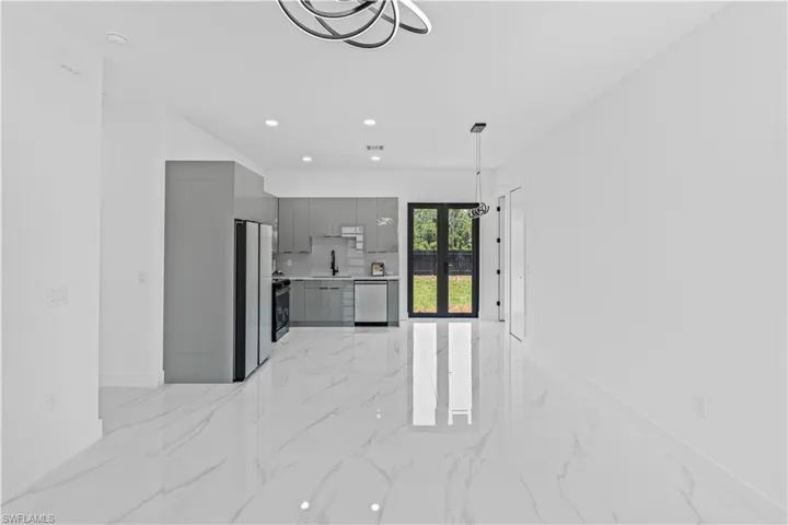 Unfurnished living room featuring light marble finish floors, baseboards, recessed lighting, and a sink