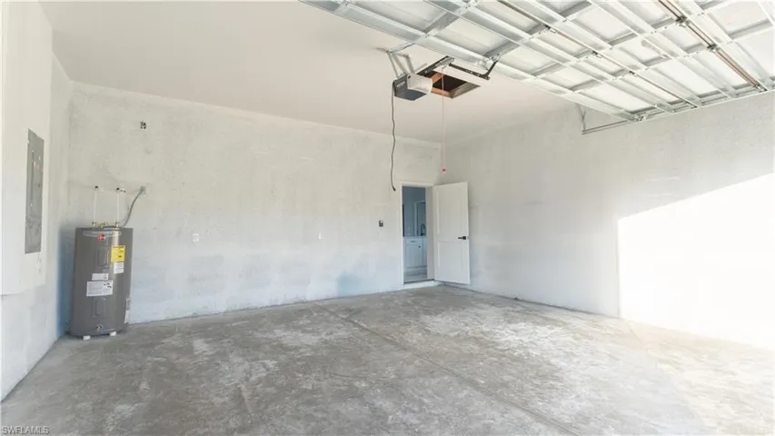 Garage featuring electric panel, a garage door opener, and water heater