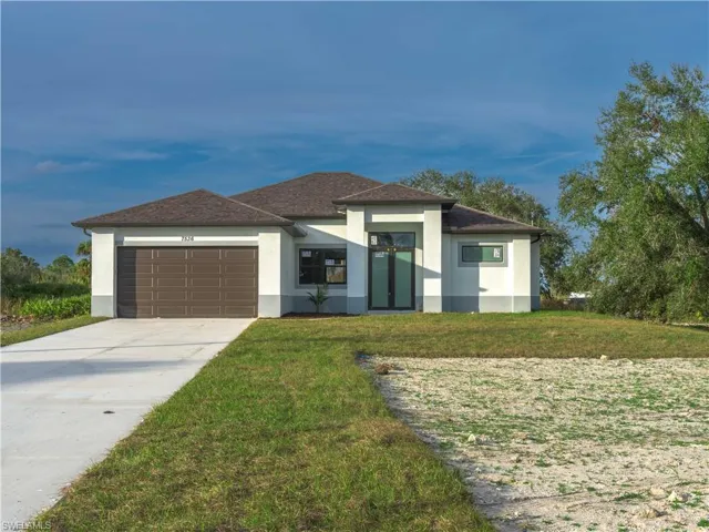 View of front of property with a front yard and a garage