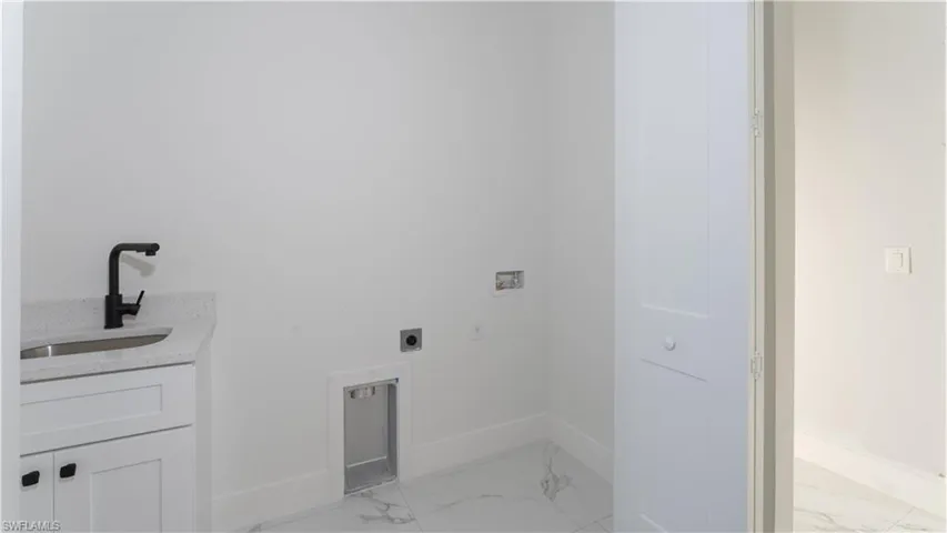 Clothes washing area featuring hookup for a washing machine, electric dryer hookup, and sink