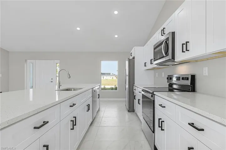Kitchen featuring appliances with stainless steel finishes, white cabinets, light stone counters, and recessed lighting