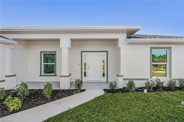 Doorway to property with stucco siding and a lawn