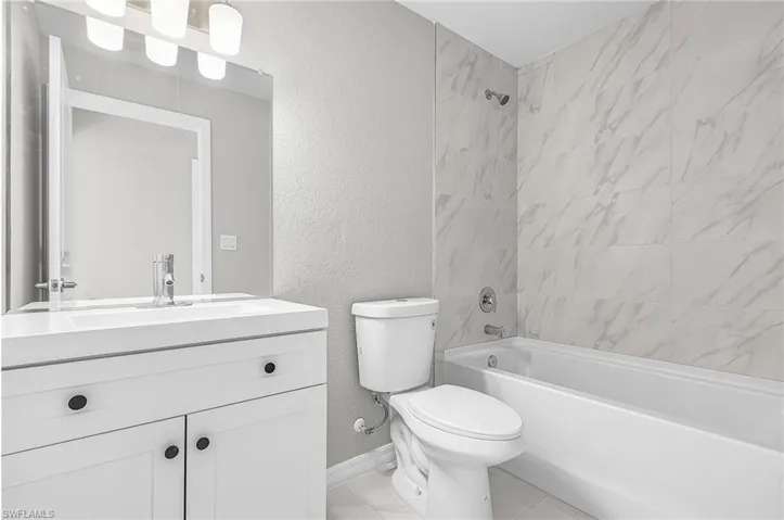 Bathroom featuring a textured wall, vanity, and shower / bath combination