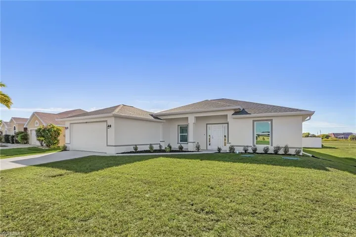 Prairie-style home with a front yard, stucco siding, driveway, and an attached garage