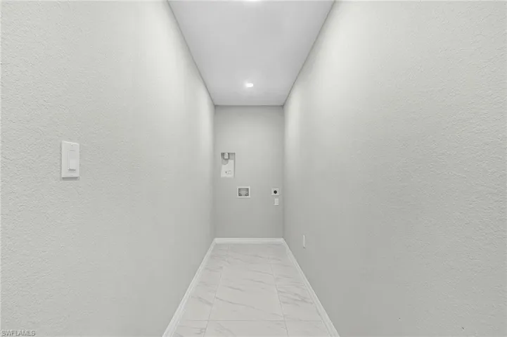 Washroom with hookup for a washing machine, electric dryer hookup, and light marble finish flooring