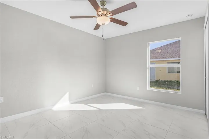 Spare room with a ceiling fan and light marble finish flooring