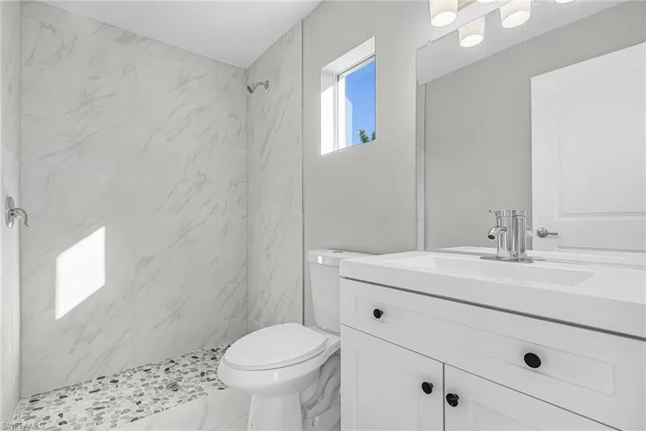 Full bathroom featuring vanity, a marble finish shower, and marble finish floors