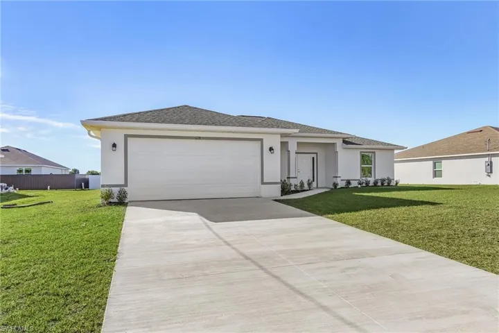 Prairie-style home featuring a front lawn, stucco siding, concrete driveway, and an attached garage
