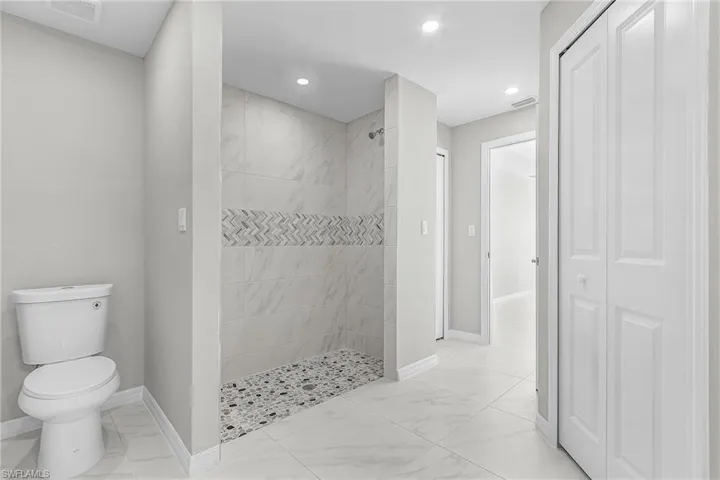 Bathroom featuring light marble finish flooring, a closet, a walk in shower, and recessed lighting