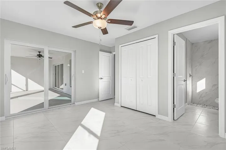 Unfurnished bedroom featuring light marble finish flooring, a ceiling fan, and a closet