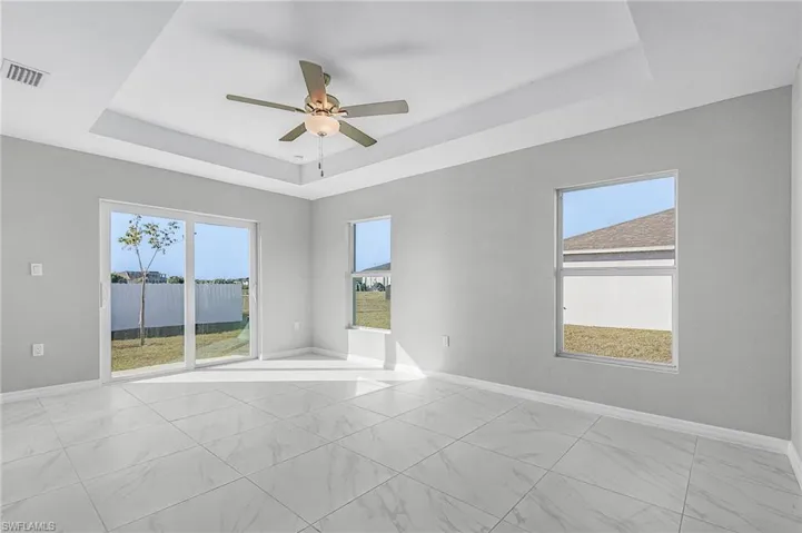 Unfurnished room featuring a raised ceiling and ceiling fan