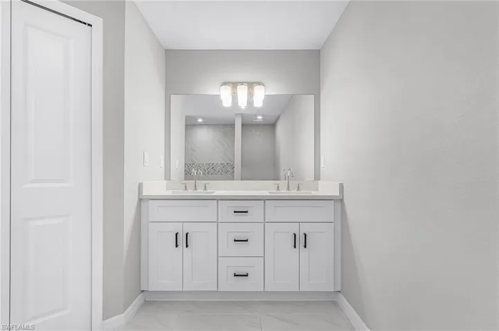 Bathroom featuring double vanity and light marble finish floors