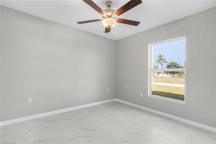 Spare room with light marble finish floors and ceiling fan