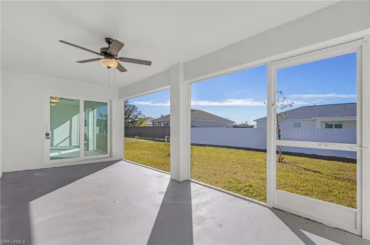 Unfurnished sunroom featuring ceiling fan, a patio, and a residential view