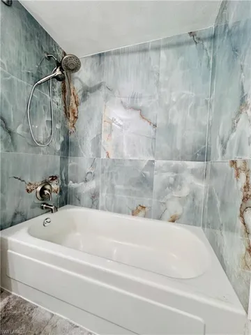 Full bath featuring shower / bathtub combination, a textured ceiling, and tile walls