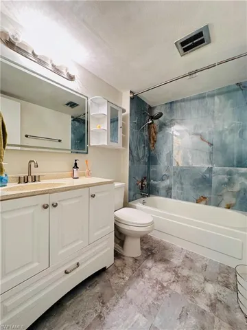 Bathroom featuring tub / shower combination, vanity, and a textured ceiling