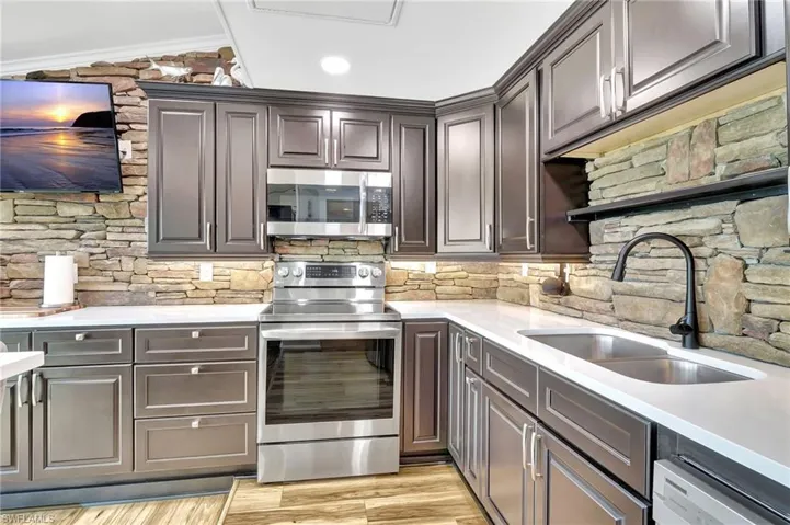 Kitchen featuring sink, stainless steel appliances, crown molding, vaulted ceiling.