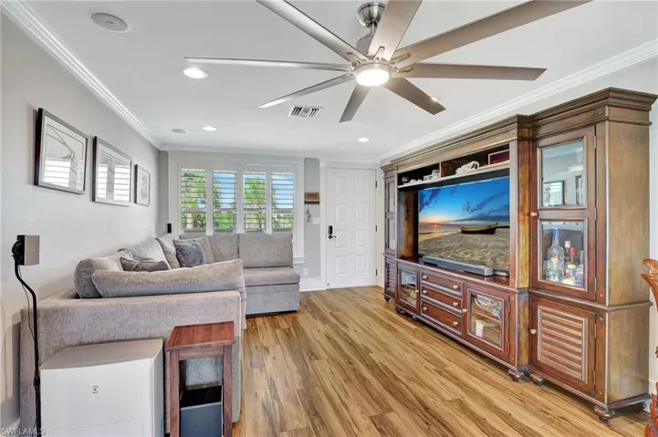 Great room with luxury vinyl floors, crown molding, large window and plantaion shutters