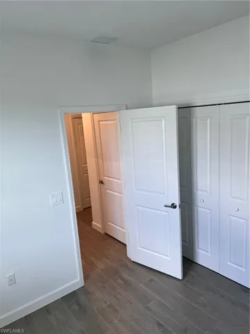 Unfurnished bedroom featuring a closet and dark hardwood / wood-style flooring