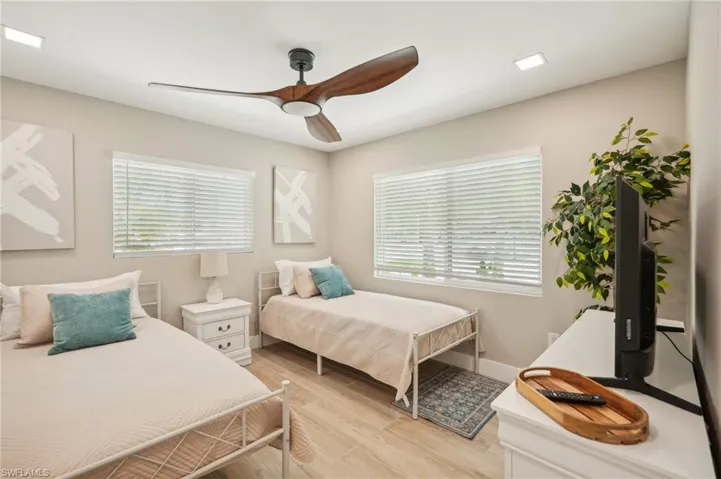 Bedroom featuring multiple windows, ceiling fan, and light hardwood / wood-style floors
