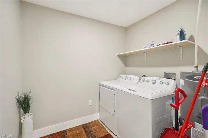 Laundry room featuring dark hardwood / wood-style flooring, water heater, and washer and clothes dryer