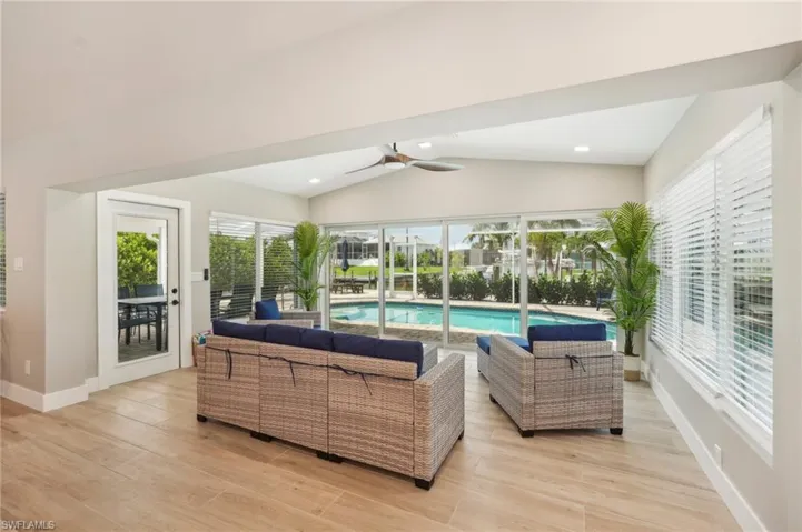 Living room with lofted ceiling, ceiling fan, plenty of natural light, and light hardwood / wood-style flooring