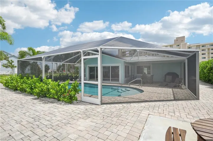 View of pool with a patio area and glass enclosure