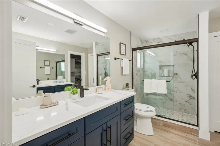Bathroom featuring vanity, a shower with shower door, hardwood / wood-style flooring, and toilet