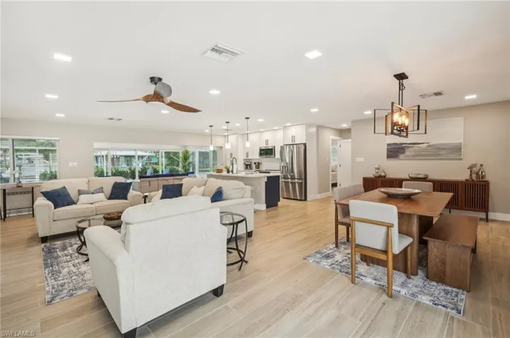 Living room featuring light hardwood / wood-style flooring, sink, and ceiling fan with notable chandelier