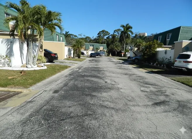 View of asphalt road featuring a residential view and curbs