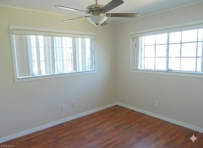 Empty room featuring ceiling fan and dark wood-type flooring