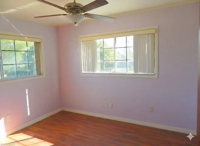 Spare room with dark wood finished floors, ceiling fan, and plenty of natural light