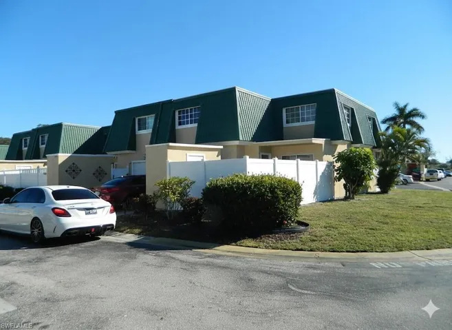 View of front of home with mansard roof and stucco siding