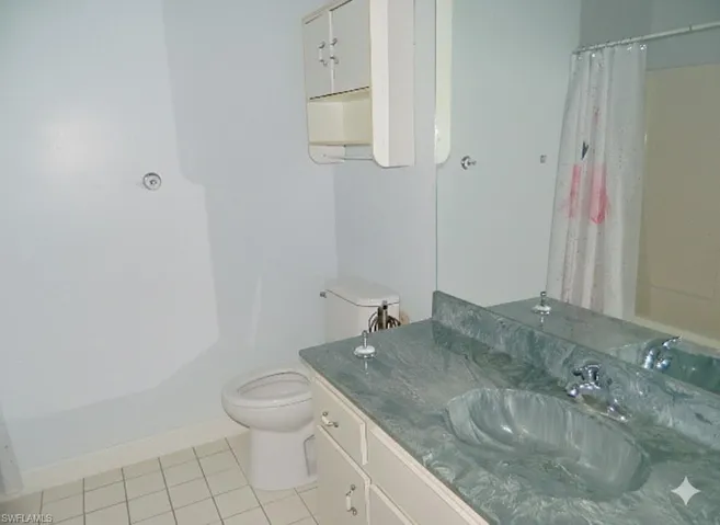 Full bathroom featuring vanity, a shower with curtain, and light tile patterned floors