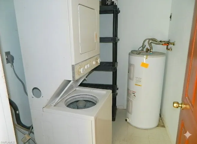 Laundry room with electric water heater and stacked washer / dryer