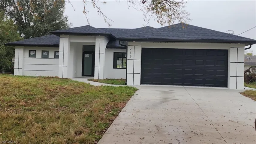 View of front facade featuring a garage and a front lawn
