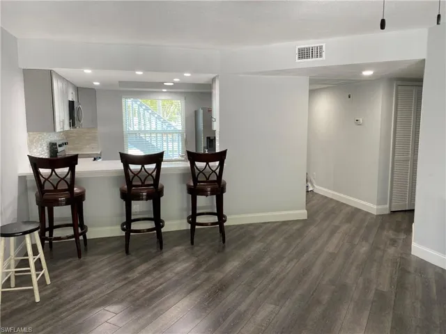 Kitchen with light countertops, dark wood-style flooring, a kitchen breakfast bar, recessed lighting, and decorative backsplash