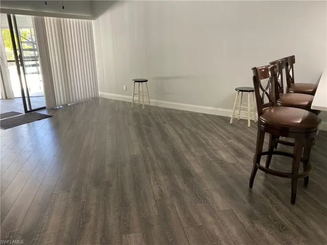 Unfurnished room featuring dark wood-style flooring and baseboards