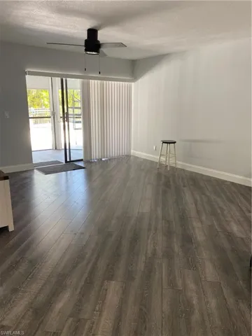 Empty room with a textured ceiling, dark wood-style flooring, and ceiling fan