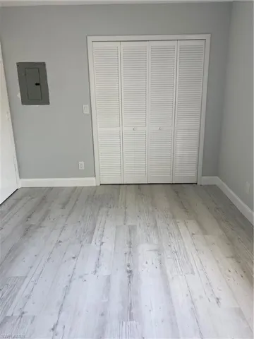 Unfurnished bedroom featuring electric panel, light wood finished floors, and a closet