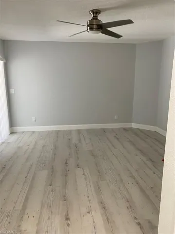 Empty room with a textured ceiling, light wood finished floors, and ceiling fan