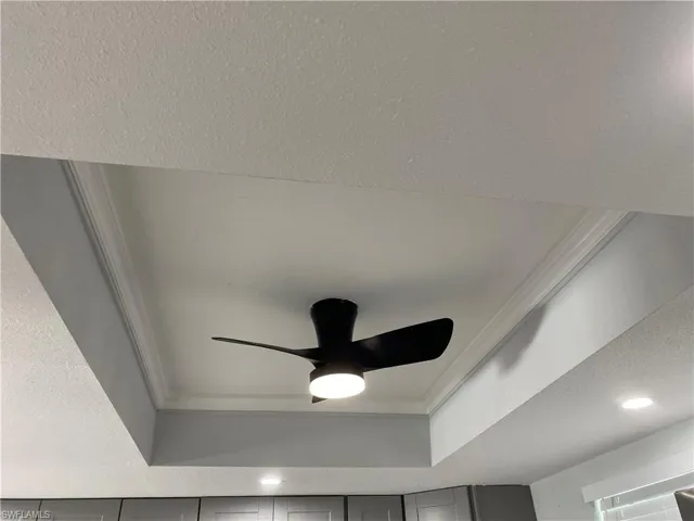 Detailed view of a textured ceiling, ornamental molding, recessed lighting, and ceiling fan