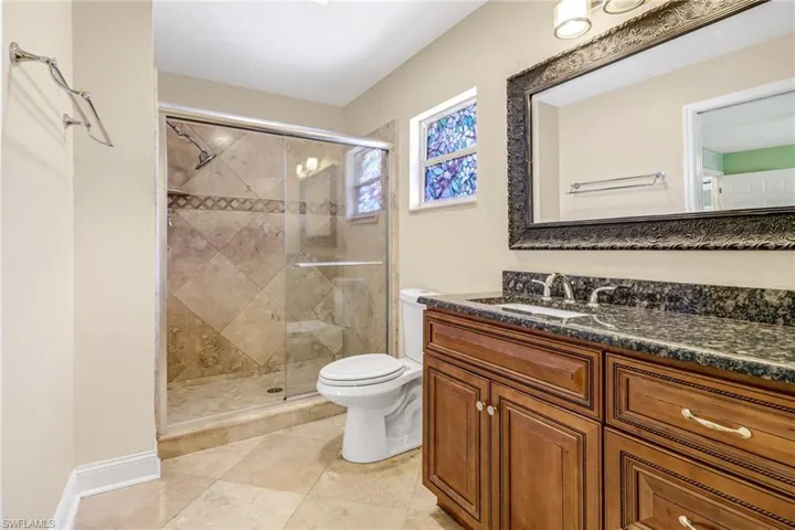 Bathroom featuring tile flooring, a shower with shower door, toilet, and vanity